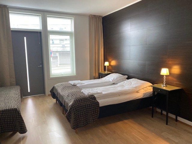 Romslig dobbeltrom med dobbeltseng, mørk fondvegg og god standard på Sentrumsgården Motell