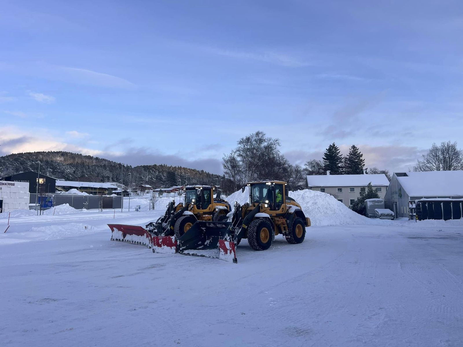To Volvo hjullastere med brøyteutstyr på snødekt plass i Rissa