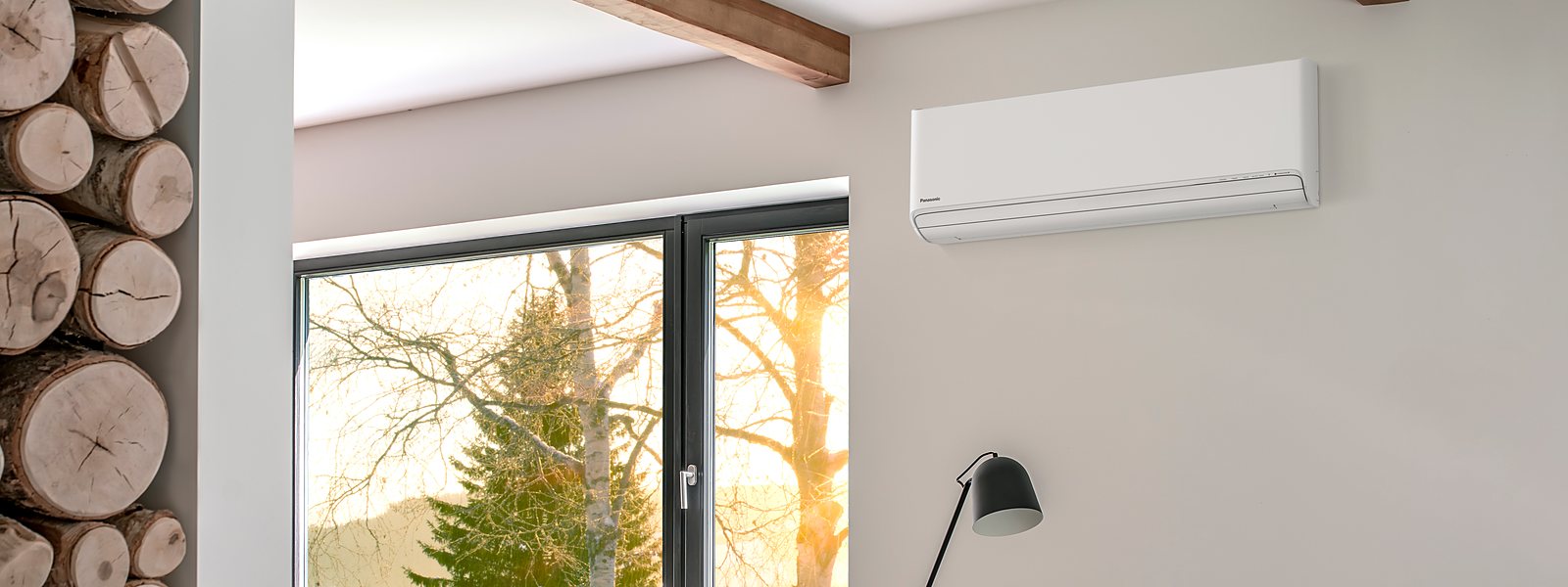 Stue med Panasonic varmepumpe, vedstabel og vintersol utenfor vinduet