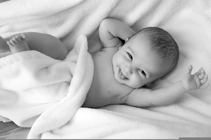 Smilende baby som ligger på et mykt teppe
