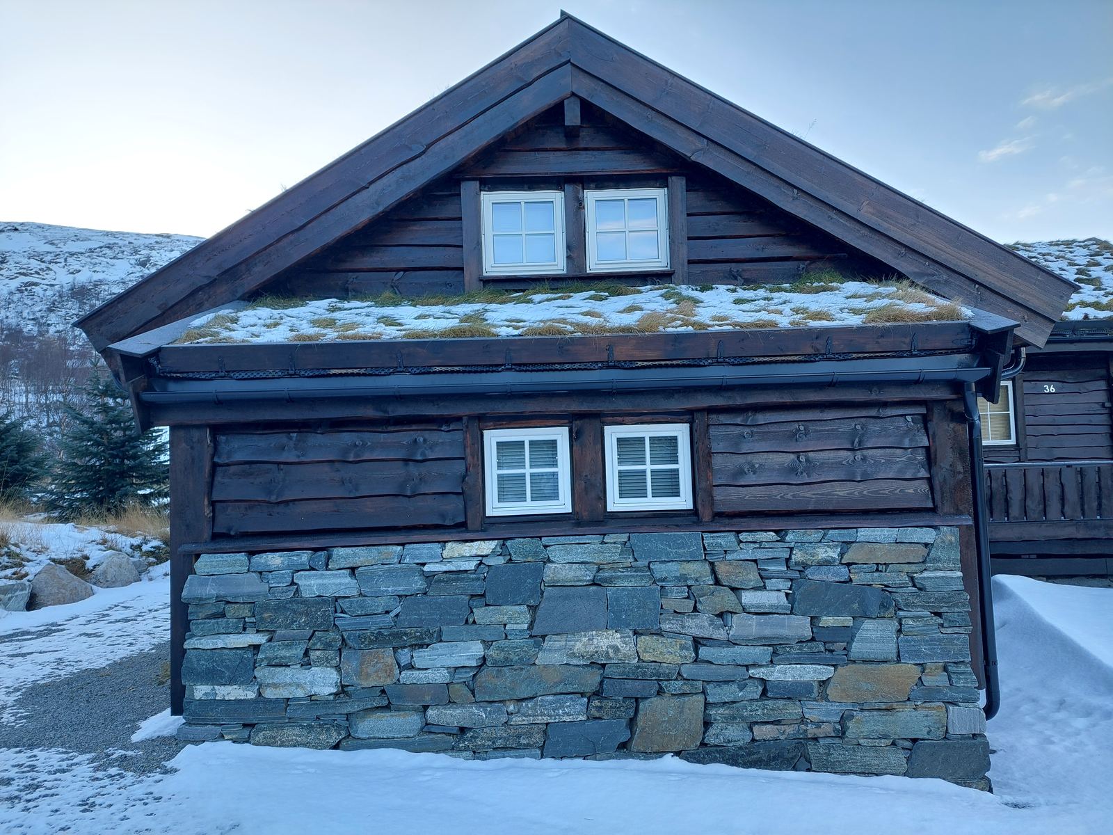 Tømret fritidsbolig med natursteinsmur og torvtak i Sirdal