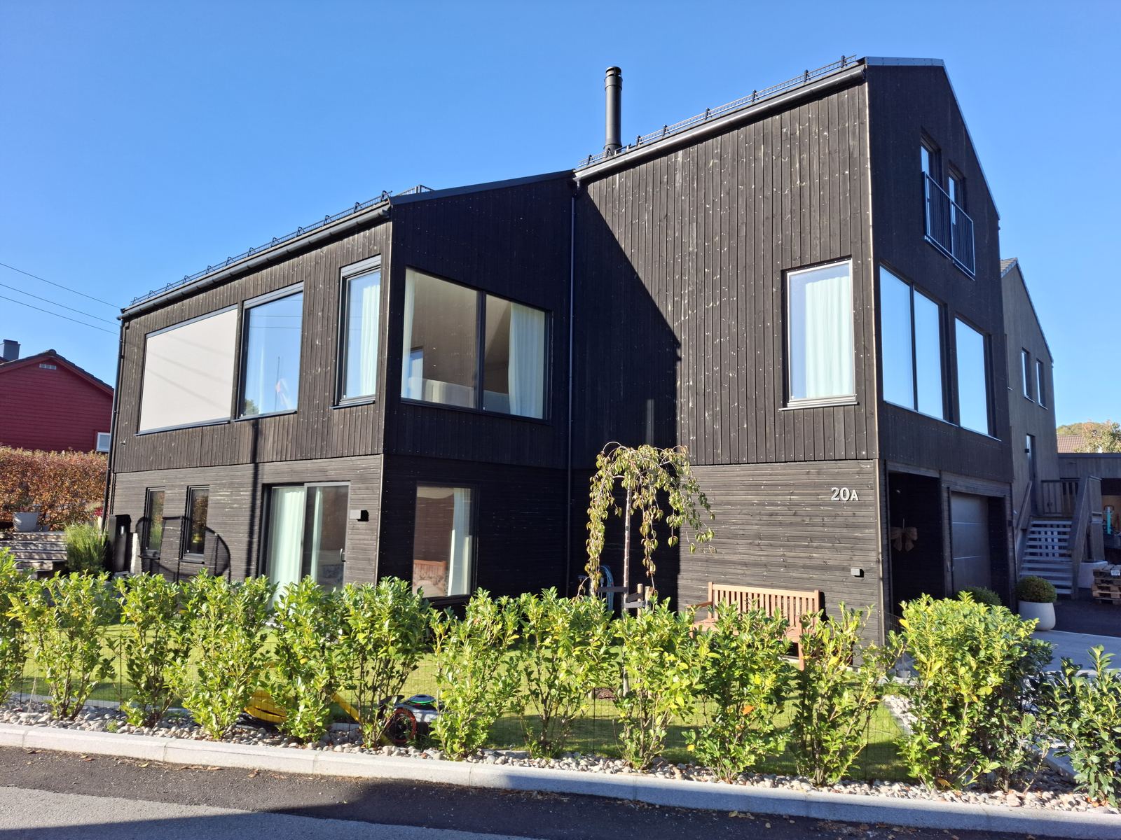 Hus med mørk trekledning og nyplantet hekk
