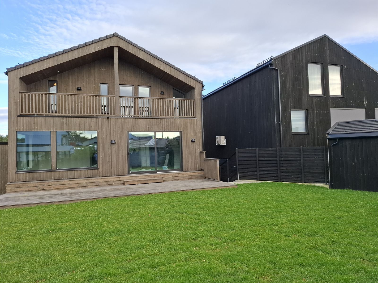 Nyoppført hus med trekledning og balkong sett fra hagen