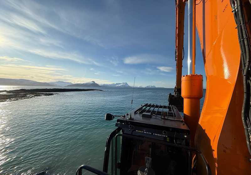 Gravemaskin i arbeid ved sjøkanten i Nordland