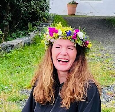 Elizabeth Pedersen ler, med blomsterkrans i håret
