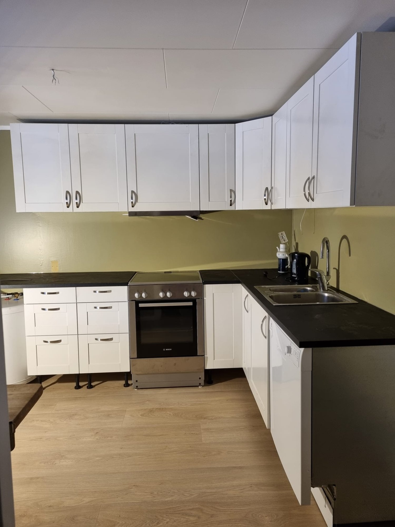 Eldhuset kjøkken – moderne hvitt kjøkken med komfyr og oppvaskmaskin