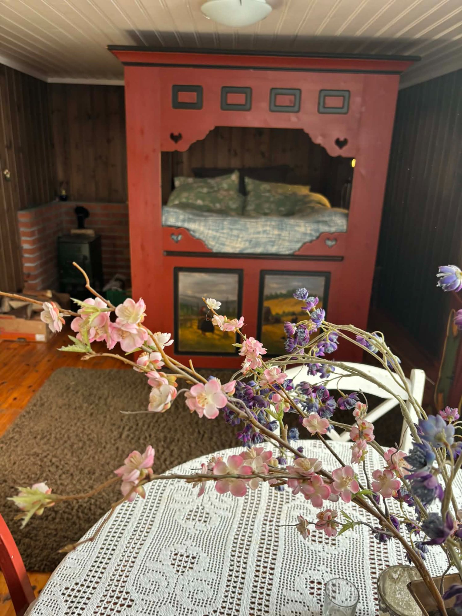 Eldhuset stue – himmelseng og blomsterdekor med peisovn i bakgrunnen