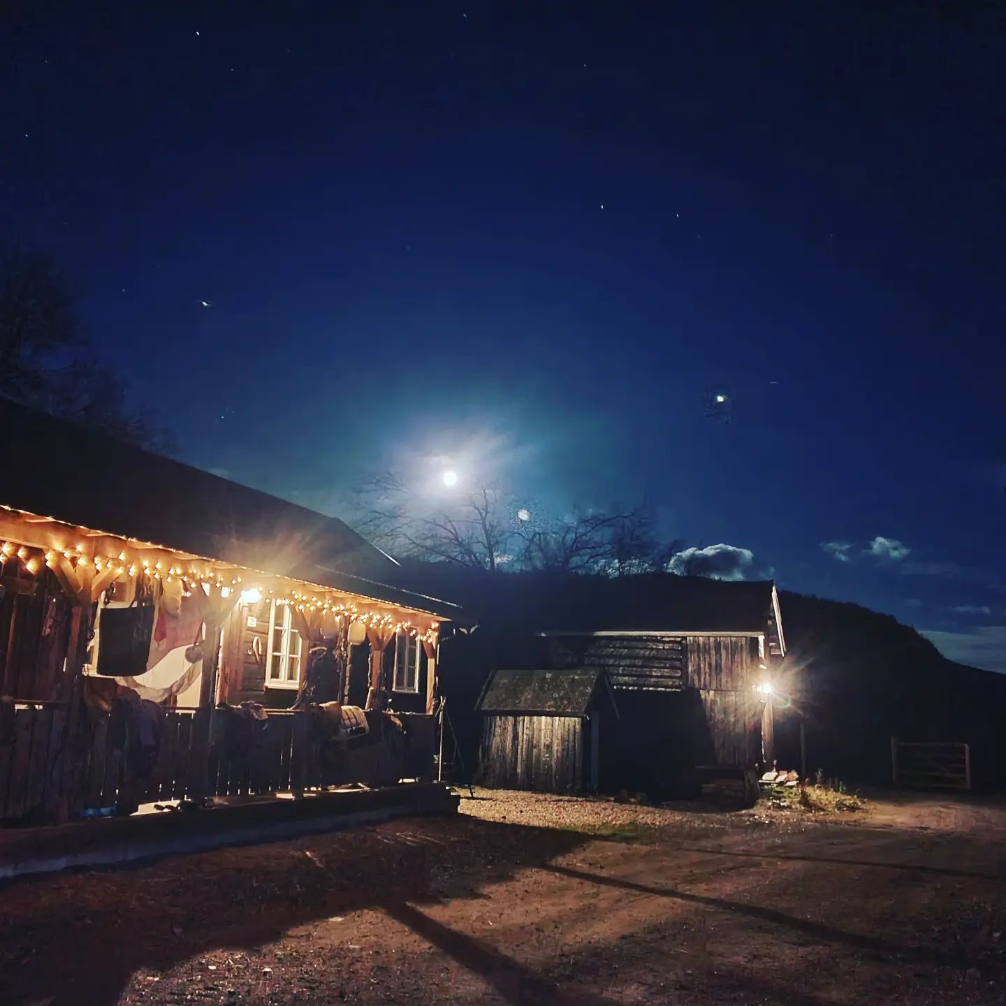 Eldhuset eksteriør om kvelden – lyslenke langs takskjegget og stjerneklar himmel