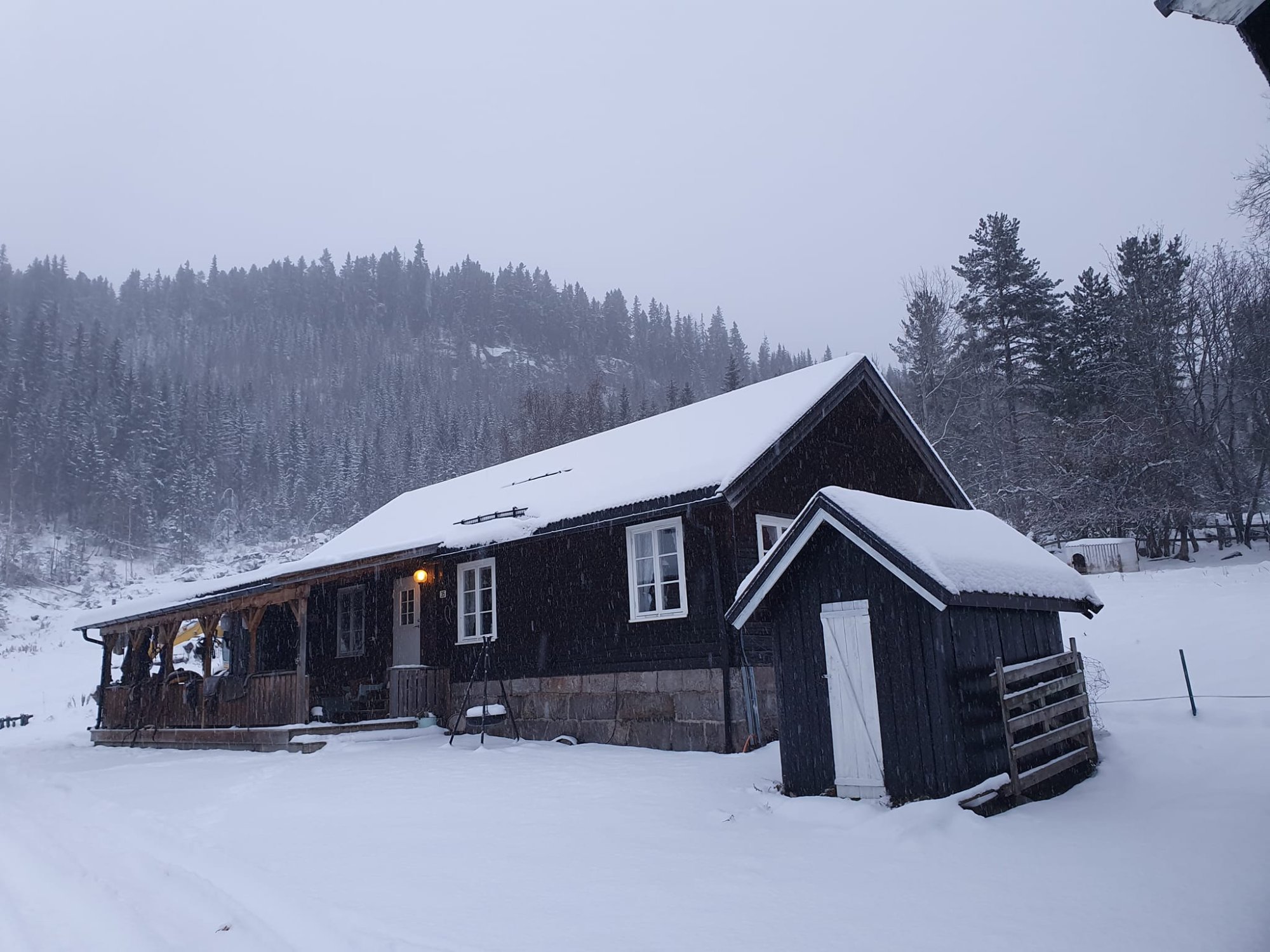 Eldhuset eksteriør om vinteren – snødekket tak og hus omgitt av skog i Fyresdal