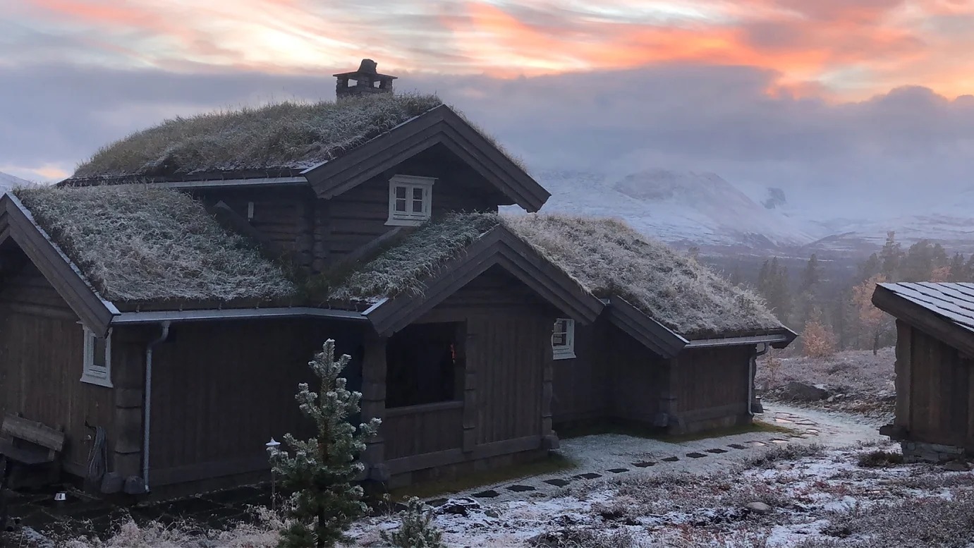 Laftehytte med torvtak i solnedgang – Phillips Saga