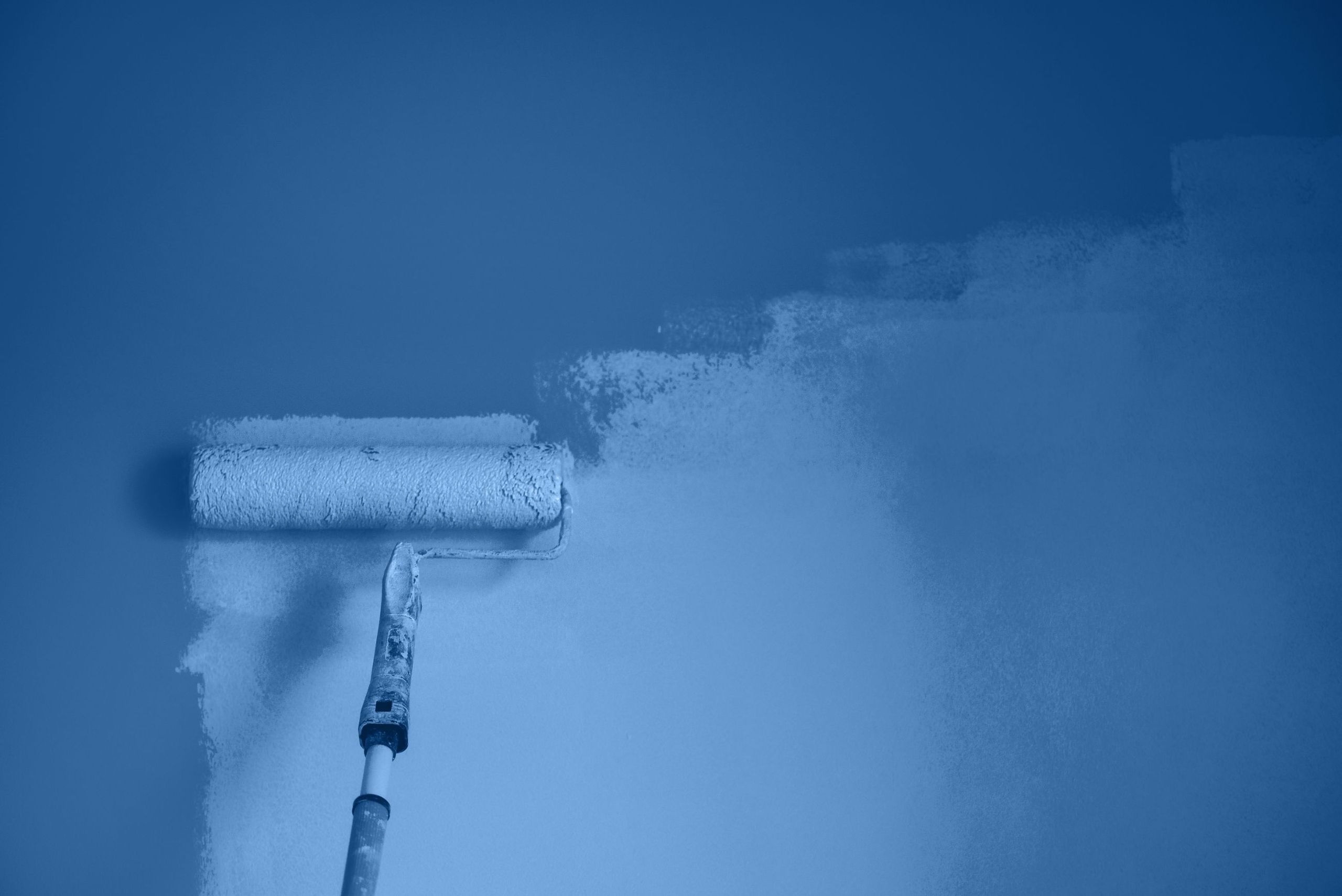 Malerrulle med blå maling på vegg