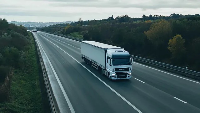 Hvit lastebil med skap kjører på motorvei