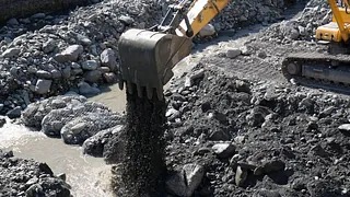 Gravemaskinskuff som tømmer masser