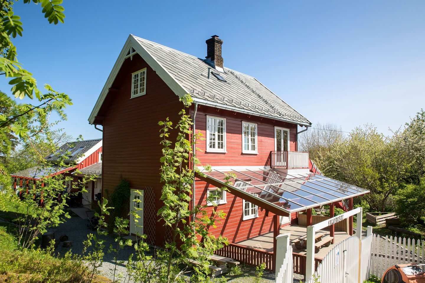Hovedhuset med glasstak over uteplassen en solrik vårdag