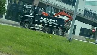 Lastebil som frakter en gravemaskin