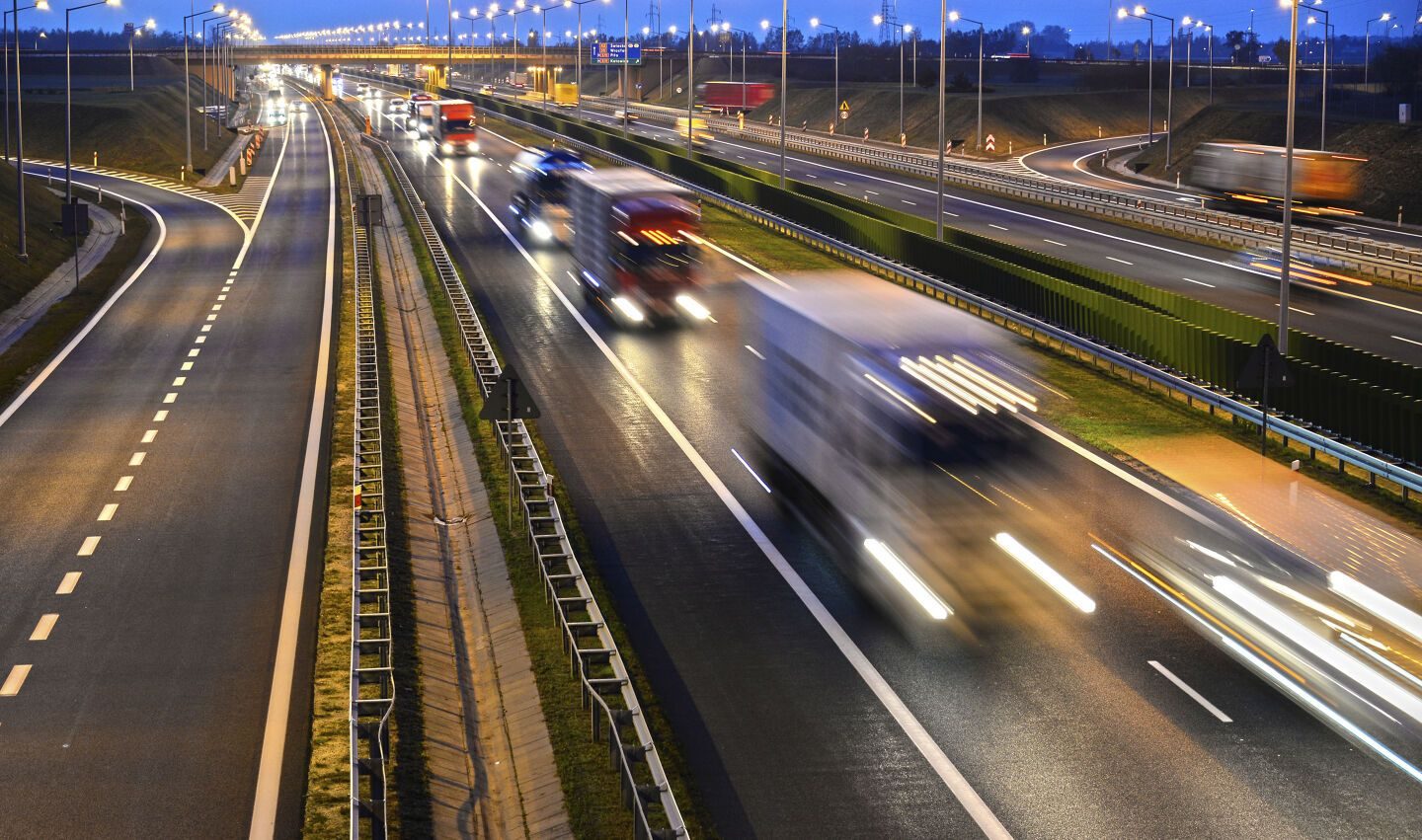 Lastebiler og biler på motorvei i kveldslys