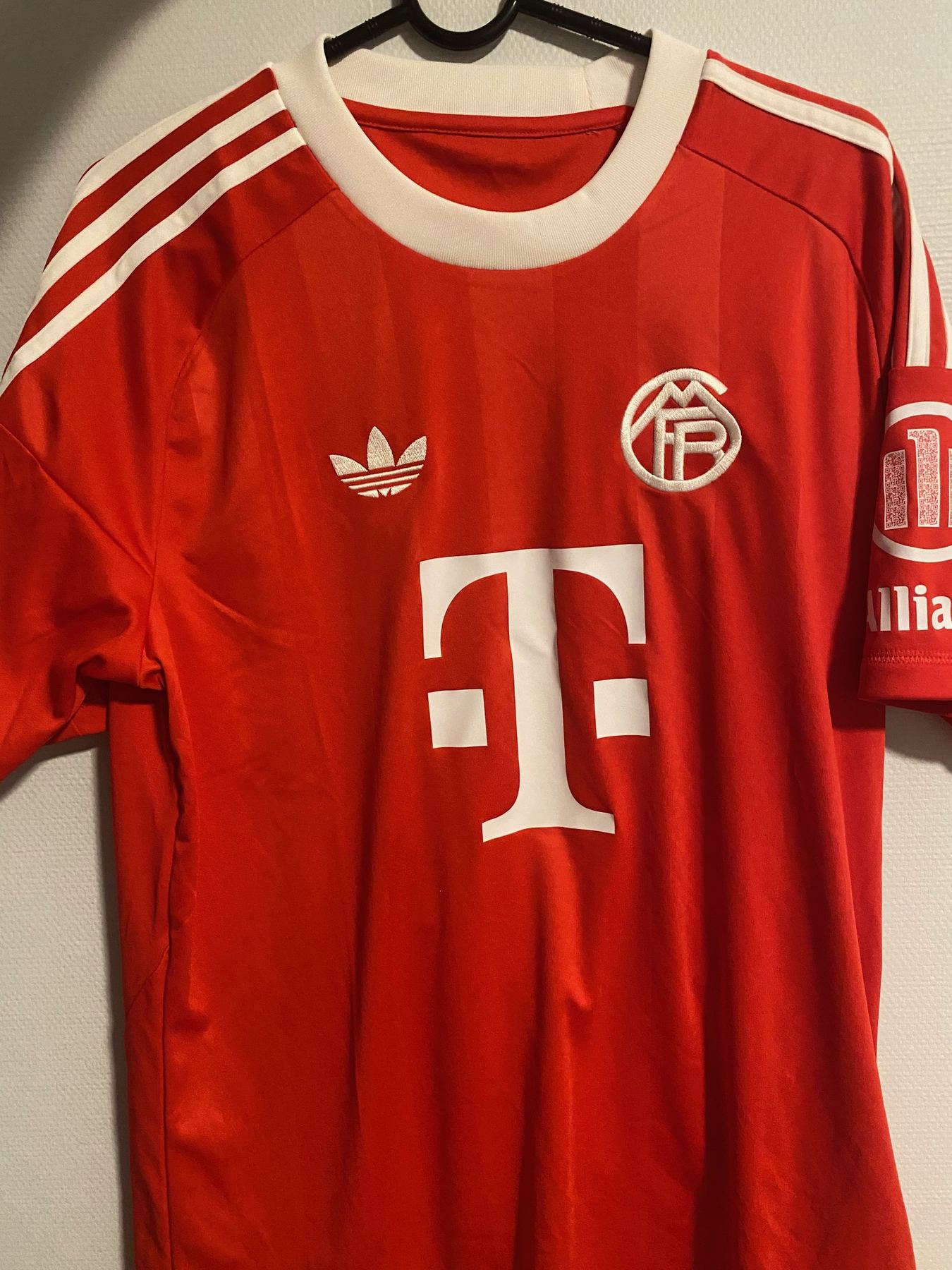 Rød FC Bayern München-drakt sett forfra med hvit krage, Adidas-kløver og retrologo på brystet