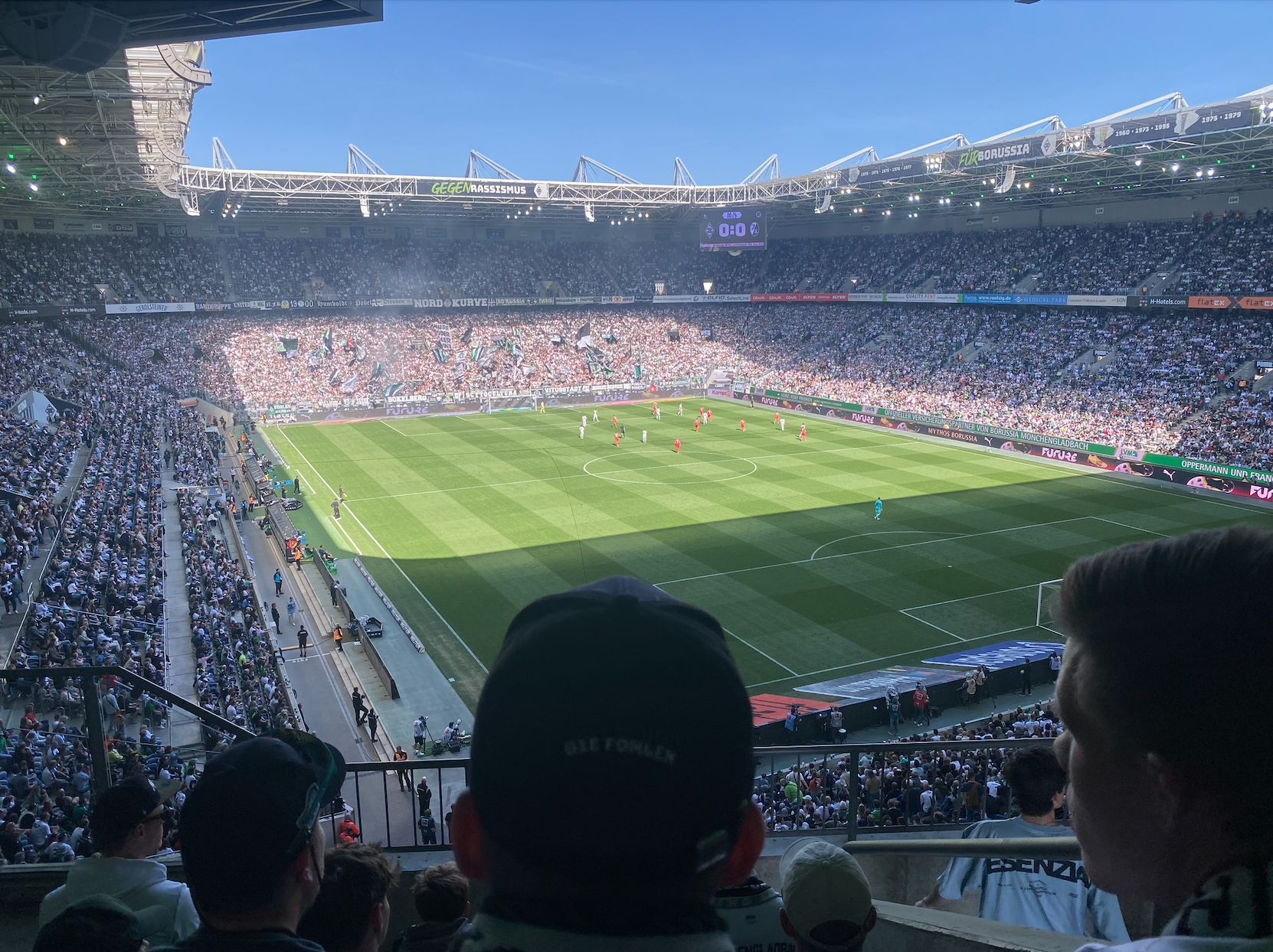Utsikt fra tribunen over en fullsatt tysk fotballstadion i sol