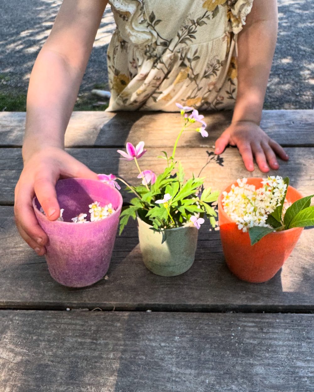 Barn arrangerer filtpotter med blomster
