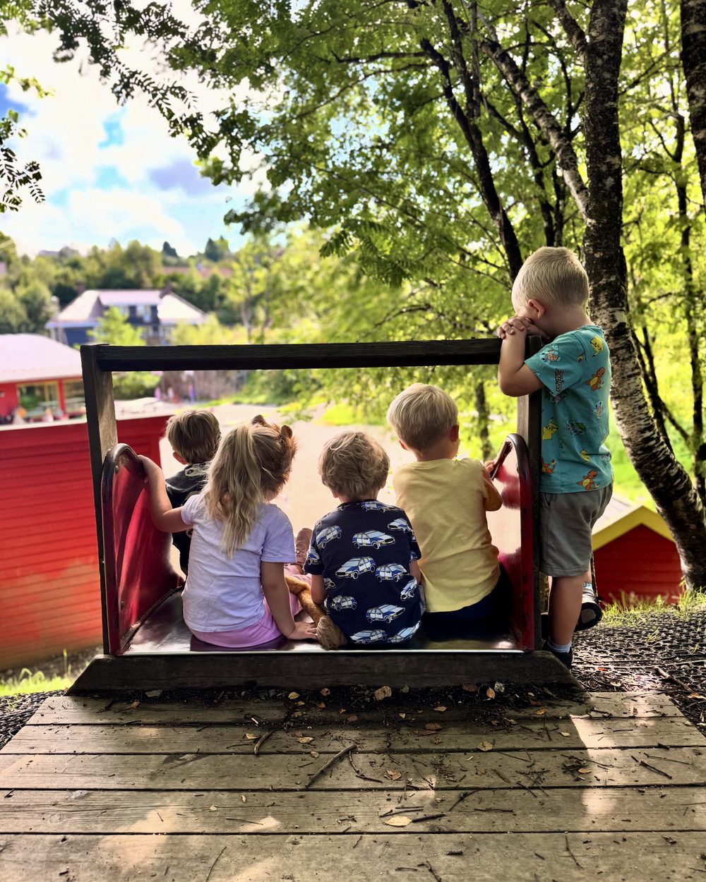 Gruppe barn sitter i lekestruktur ute på fin dag