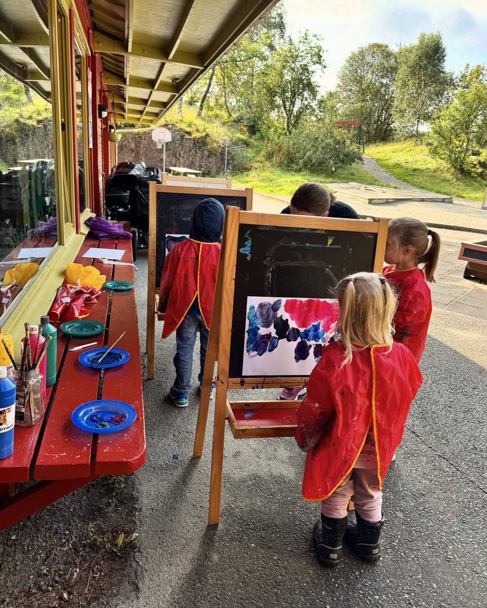 Barn maler ved staffelier ute i barnehagen