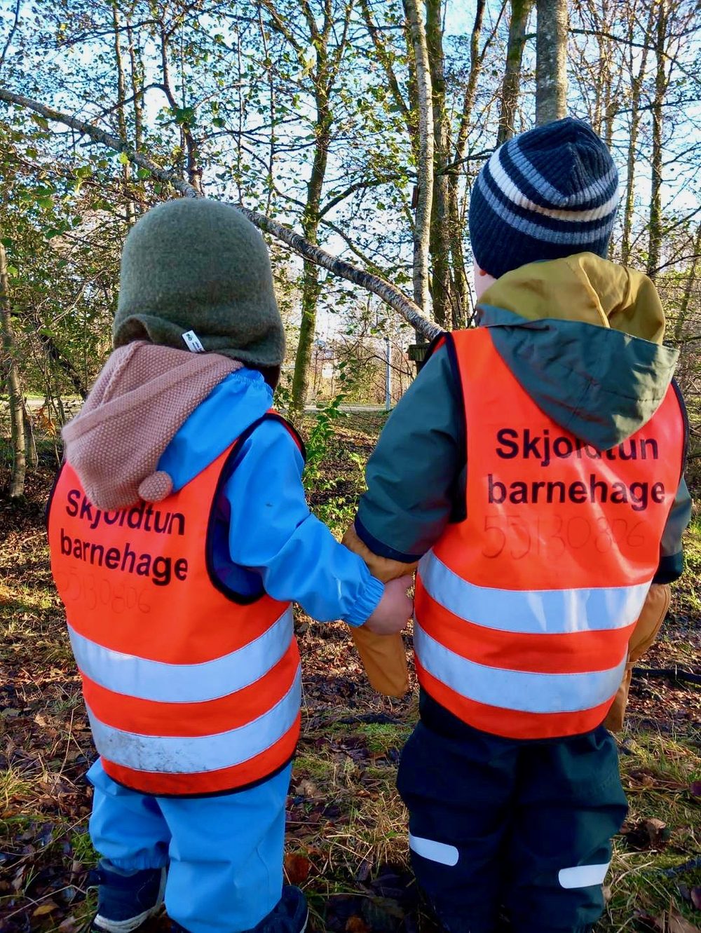 To barn med Skjoldtun barnehage-vester på tur i skogen