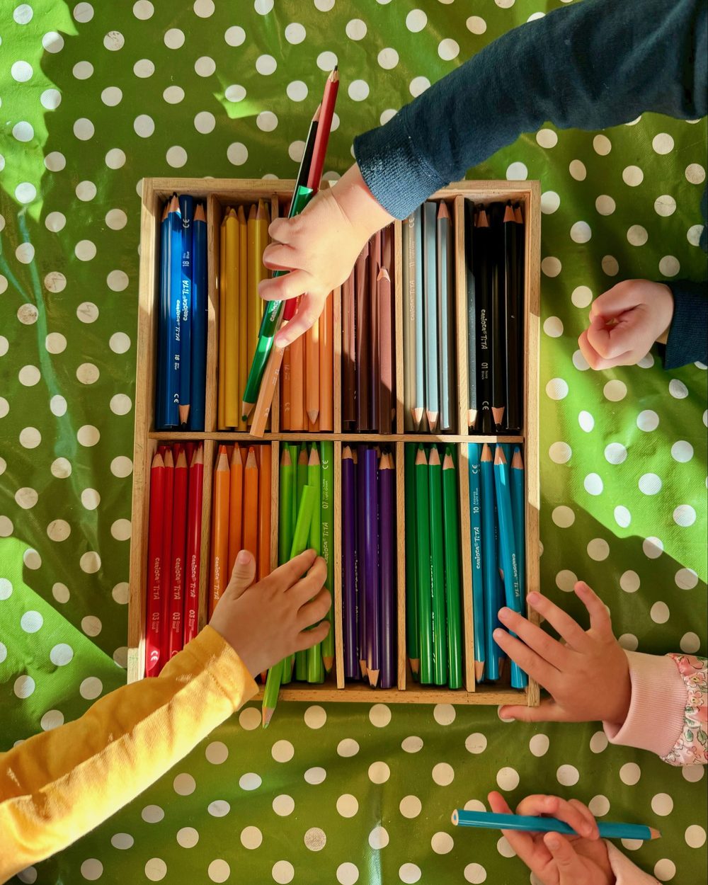 Barns hender plukker fargeblyanter fra kasse