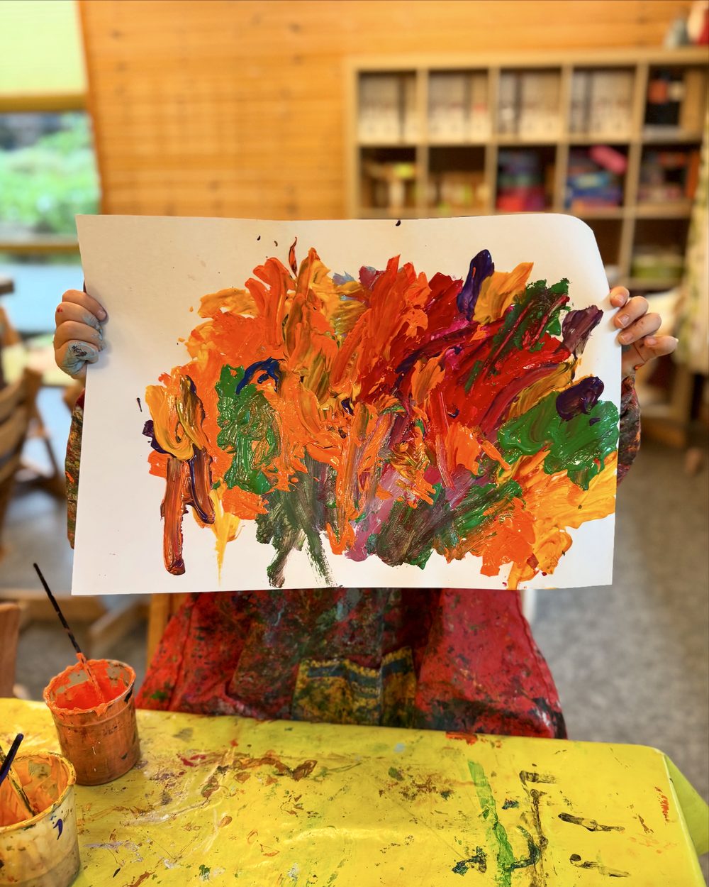 Barn viser stolt frem sitt fargerike maleri