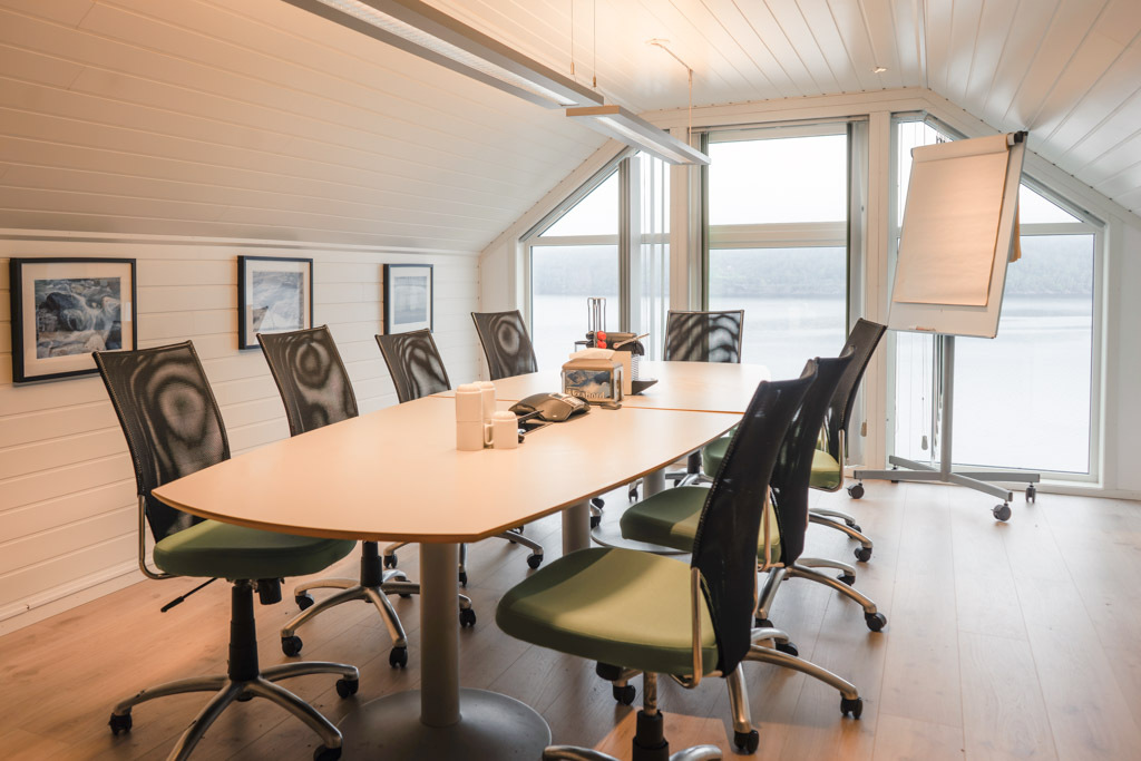 Konferansebord med mange stoler rundt i møtelokale.