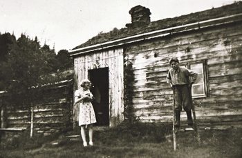 REF-0385 Skjervsætra 1942.
Inger med katta og Arnt på stylto.T.v. gammeldelen frå 1800-talet, delen t.h. bygd ca 1936.