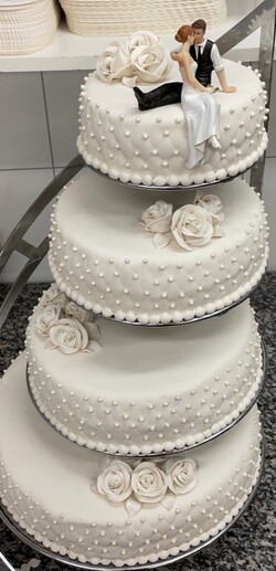 4 etg kake pyntet med håndlagde hvite marsipanroser. Diamantmønster og perler på sidene.