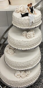 4 etg kake pyntet med håndlagde hvite marsipanroser. Diamantmønster og perler på sidene.