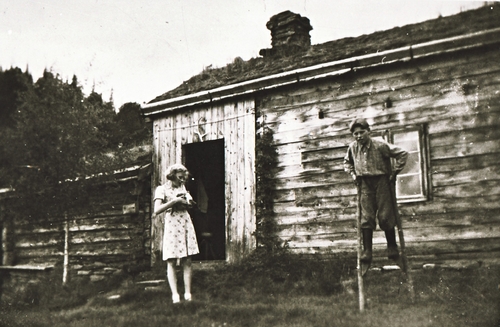 REF-0385 Skjervsætra 1942.
Inger med katta og Arnt på stylto.T.v. gammeldelen frå 1800-talet, delen t.h. bygd ca 1936.